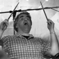 Black and white photo of drummer raising sticks in the air