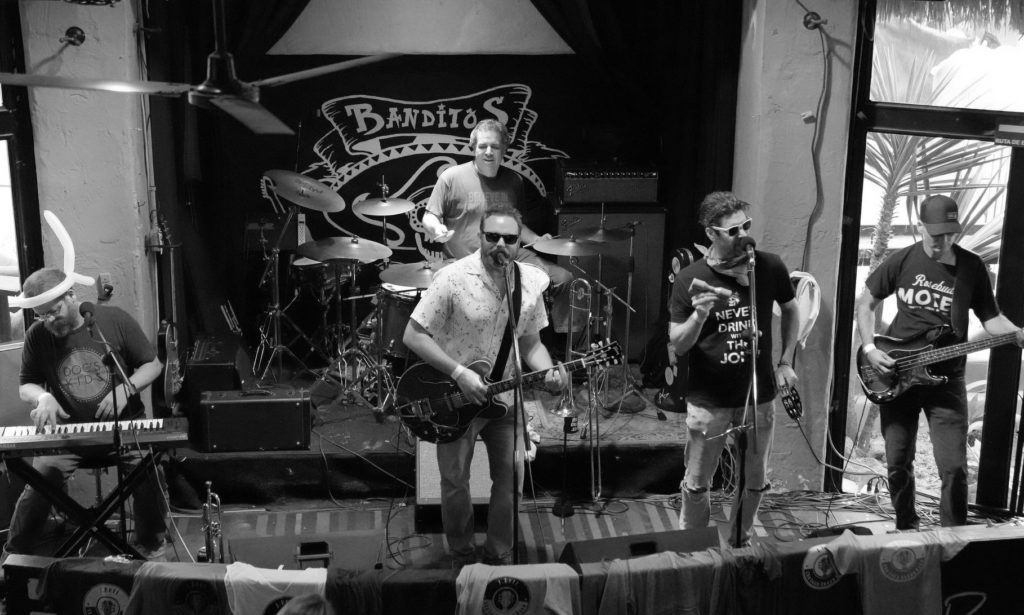 Black and white photo looking down on five band members on stage