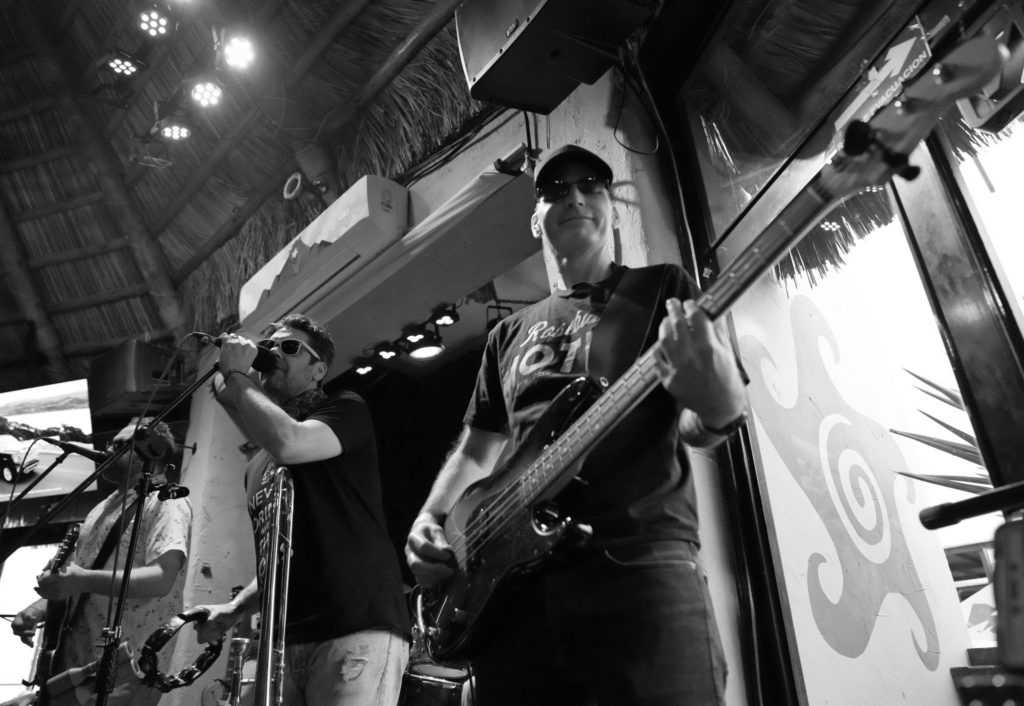 Black and white photo looking up at two singers and a bassist on stage