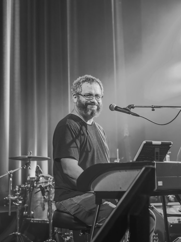 keyboardist smiles at the camera in black and white