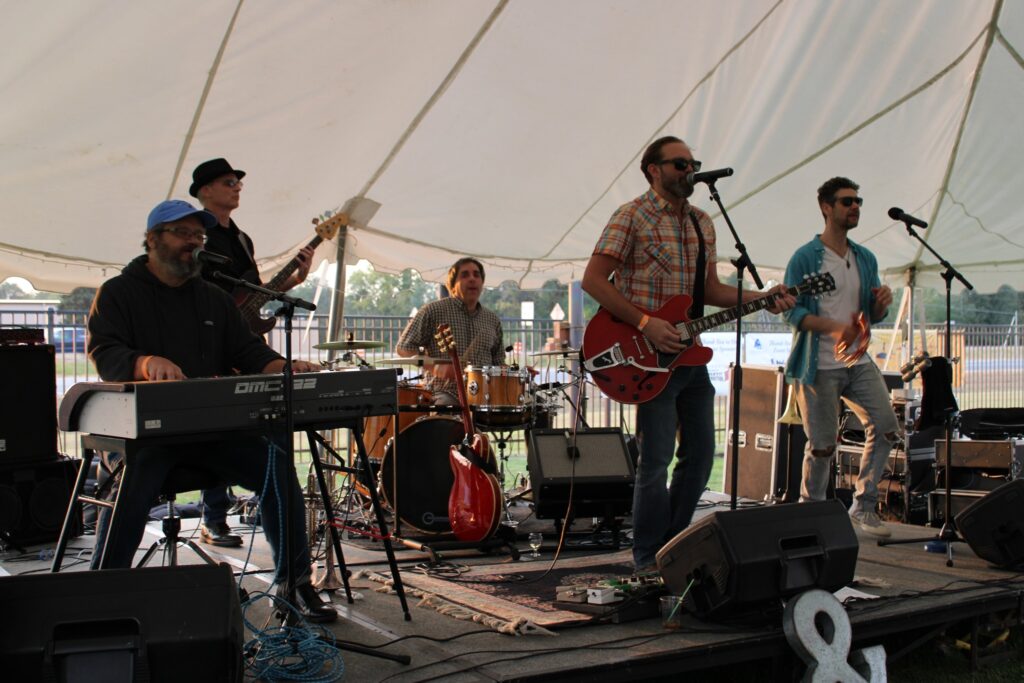 Outdoor stage with five rock musicians